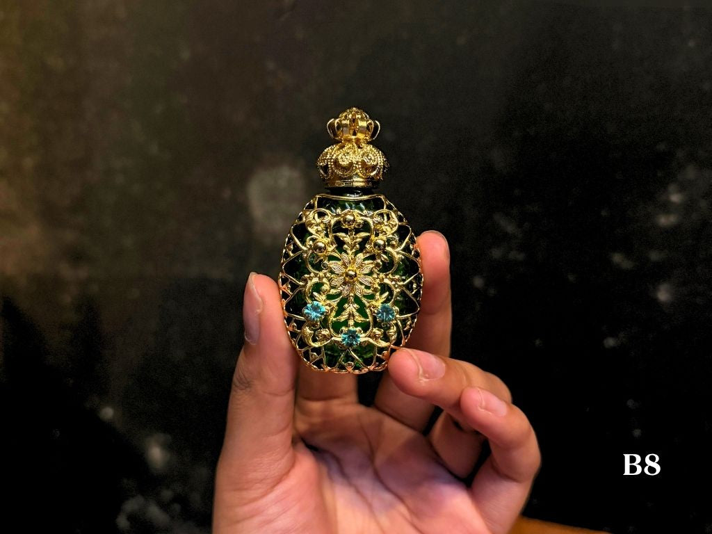 Czech Republic handmade decorative oil perfume bottle with intricate design. Green bottle with gold and electric blue gems for design.