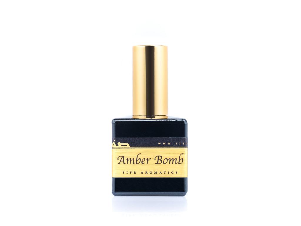 "50ml spray bottle of Eau De Parfum placed elegantly on a white background. The bottle is sleek and black, with a polished gold cap. The label on the bottle is designed in gold and black, featuring Sifr Aromatics' logo and the perfume name 'Amber Bomb' The overall aesthetic is clean and sophisticated, highlighting the high-quality craftsmanship of the product.